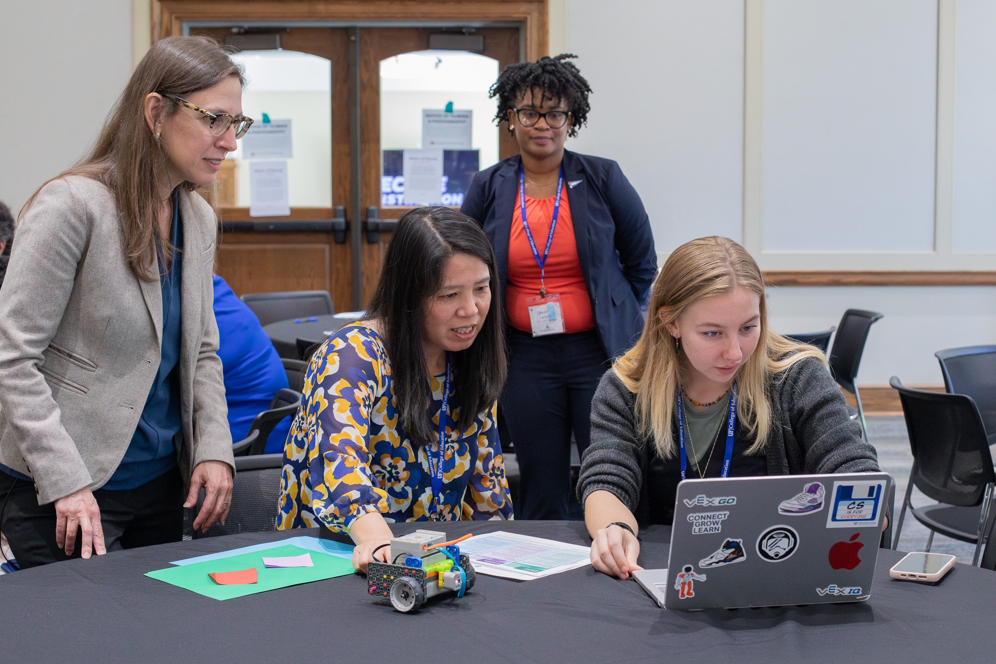 CS Everyone Center team members Maya Israel and Latoya Chandler look on as two women look intently at a laptop screen.