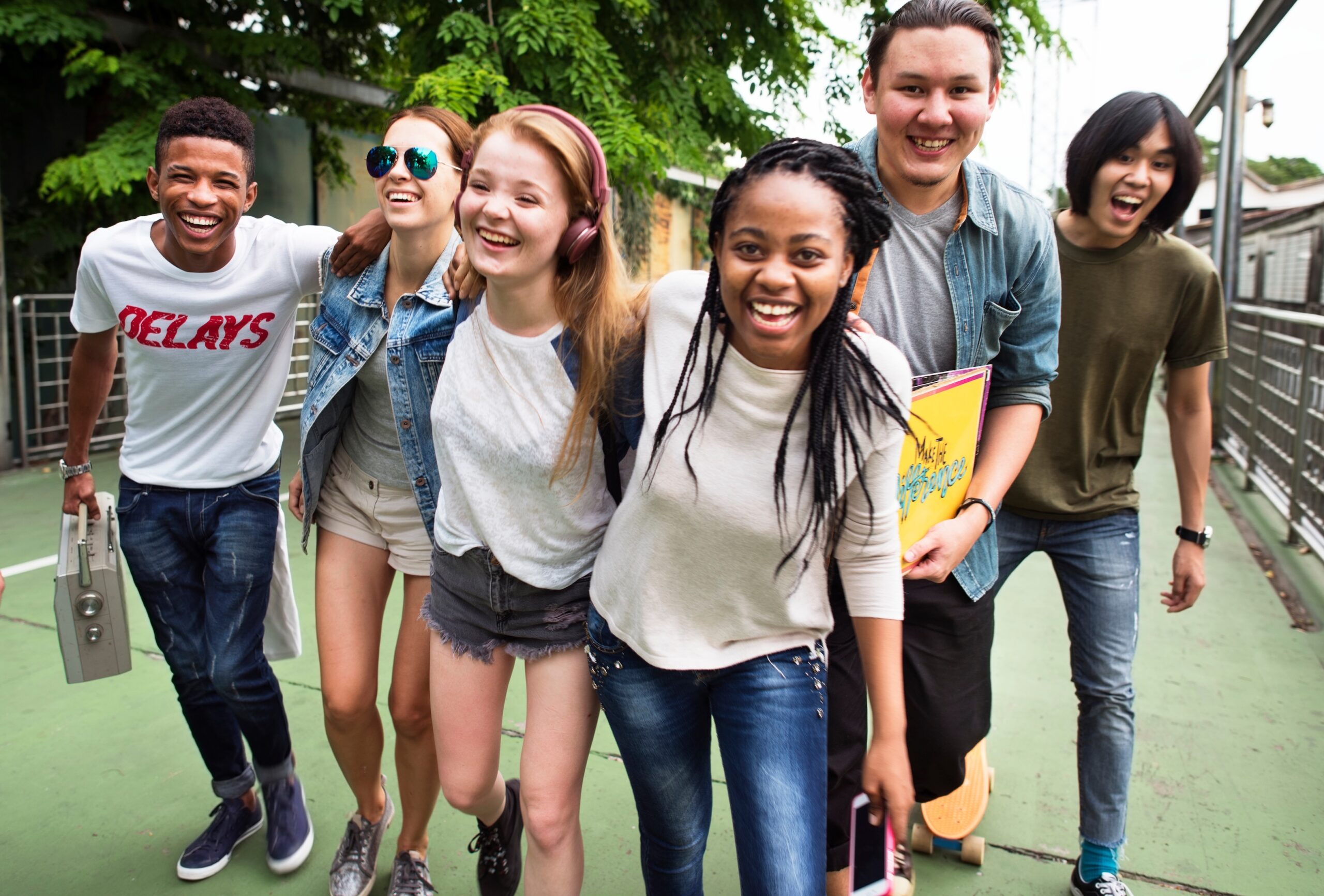 Group of six young adults smiling and walking together outdoors.